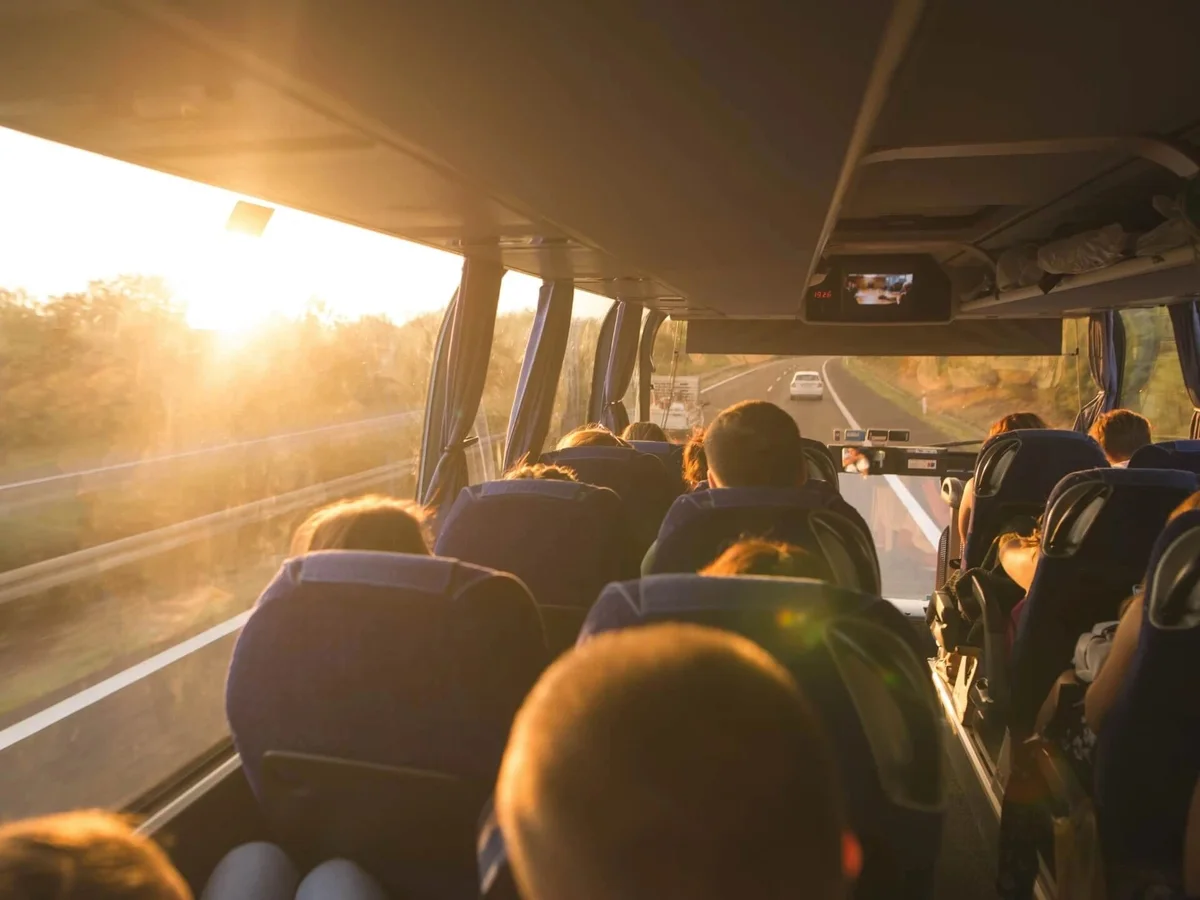 Passagers dans un autocar sur la route au coucher du soleil.